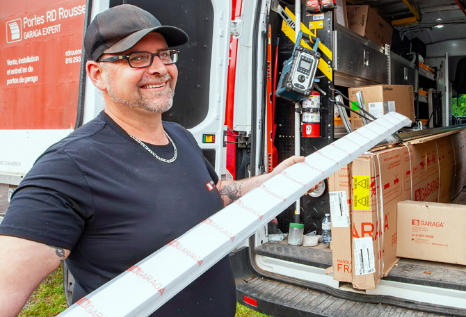 Technicien porte de garage souriant de Portes RD Rousseau avec son camion de service